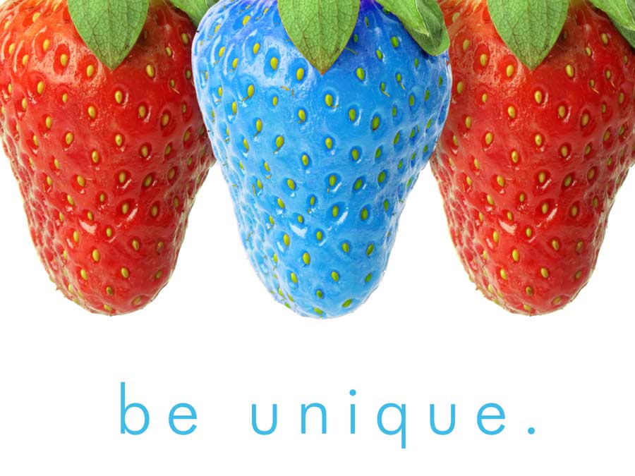Image of three strawberries, two red and one pale blue right in the middle, with "be unique" in blue.